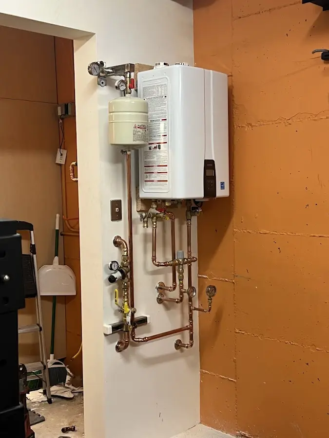 Plumbing technician inspecting water heater connections in Hubbard
